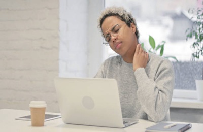 Young African Woman having Neck Pain while using Laptop in Office Young African Woman having Neck Pain while using Laptop in Office