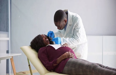 Dentist Treating Teeth Of Young Pregnant Woman Patient Lying In Clinic Dentist Treating Teeth Of Young Pregnant Woman Patient Lying In Clinic